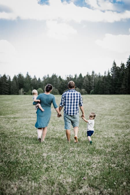 Familie von hinten läuft über eine Wiese