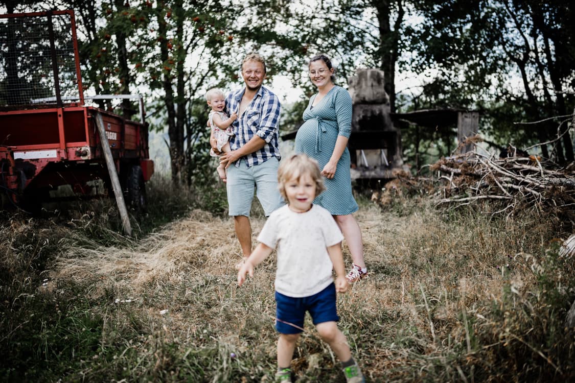 Junge rennt auf die Kamera zu. Familie steht im Hintergrund.