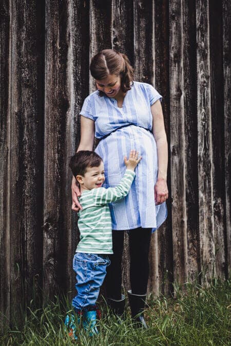 Junge hält die Hand auf den Babybauch der Mutter