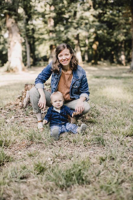 Mutter auf einer Wiese in der Hocke hinter ihrem Sohn