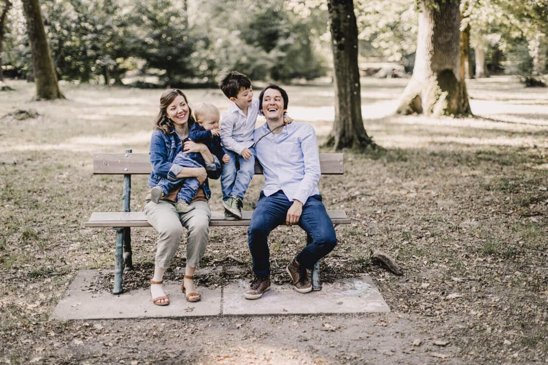Familie sitzt auf einer Bank und albert herum