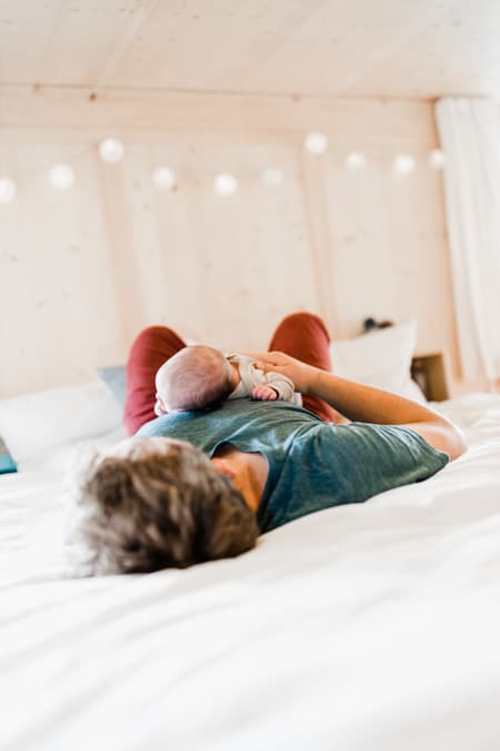 Papa mit Baby auf dem Bauch liegend