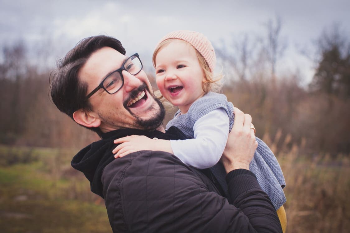 Vater mit Tochter auf dem Arm lachend