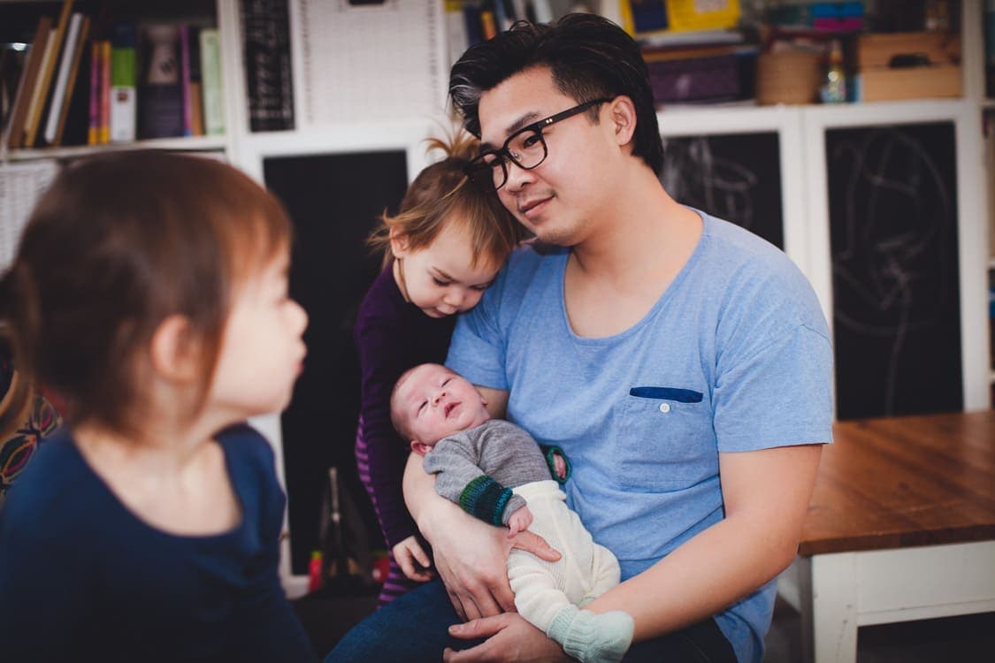 Vater mit seinen drei Kindern im Wohnzimmer.