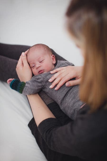 Mutter hat ihr Baby auf dem Schoß liegen und strechelt es