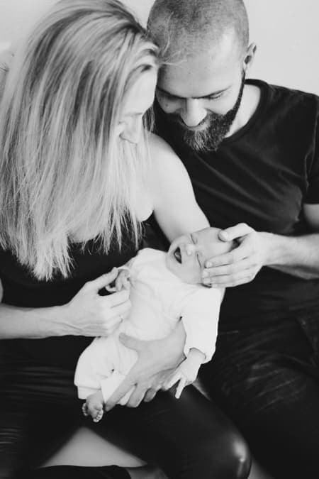 Eltern halten ihr Baby gemeinsam im Arm und schauen es an