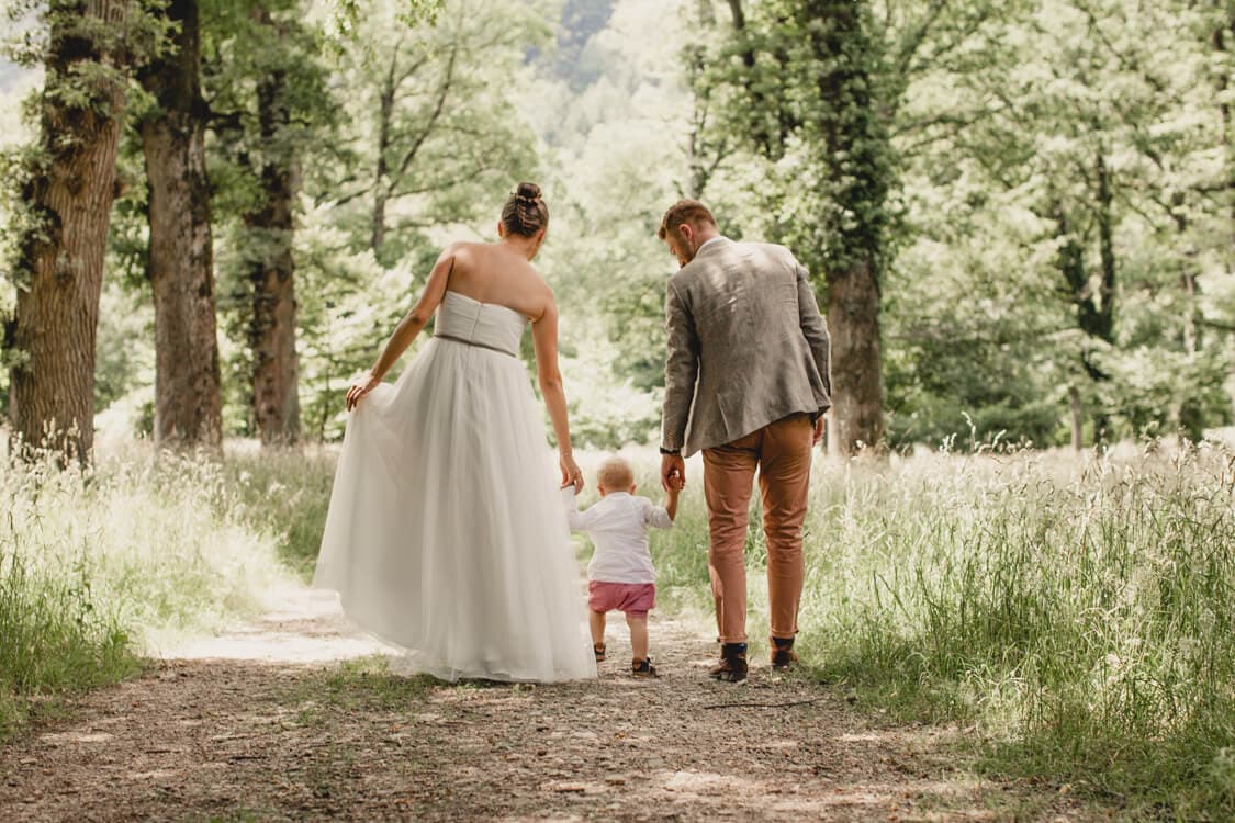 Brautpaar von hinten mit kleinem Sohn an der Hand