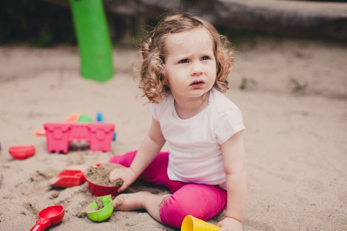Kleines Mädchen beim sandeln im Sandkasten