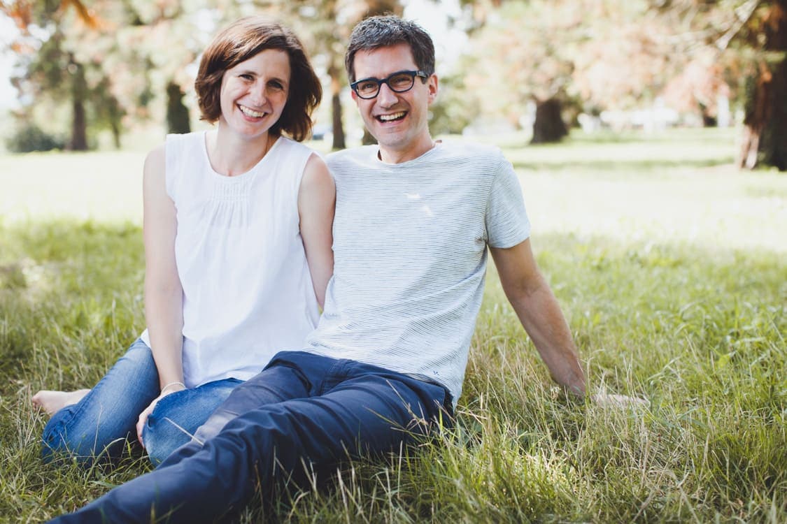 Eltern sitzen auf einer Wiese