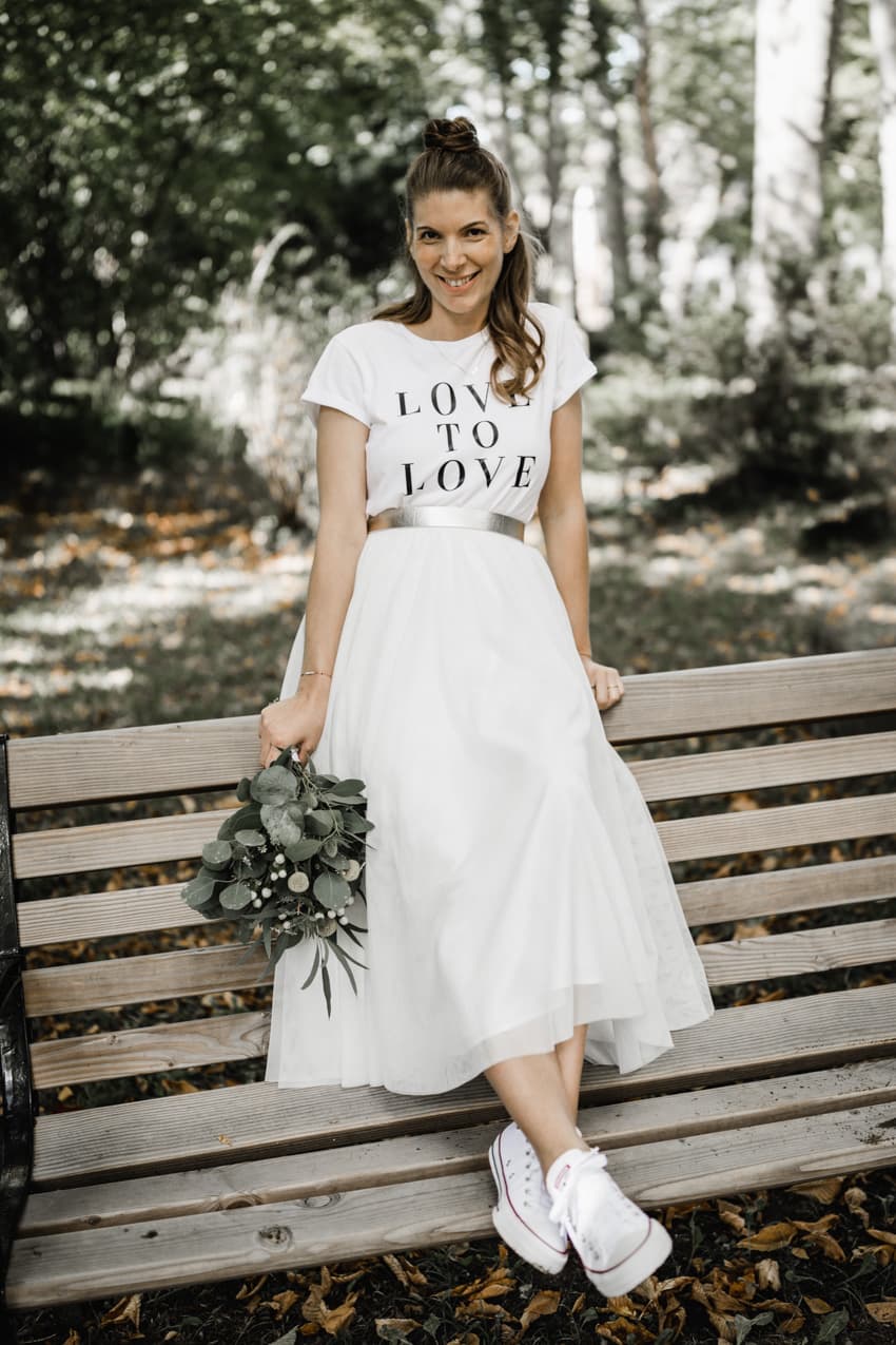 Braut sitzt auf einer Parkbank