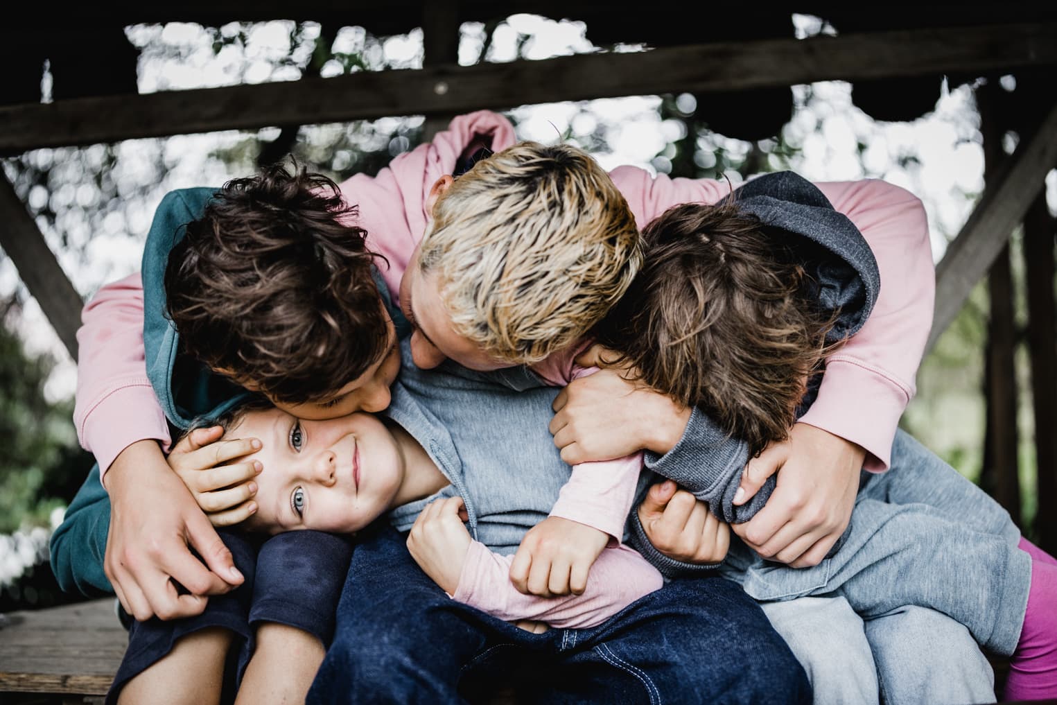 Mädechen wird von ihren drei großen Brüdern gekuschelt