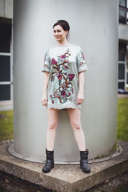 Frau mit Paillettenkleid steht vor einem Schornstein