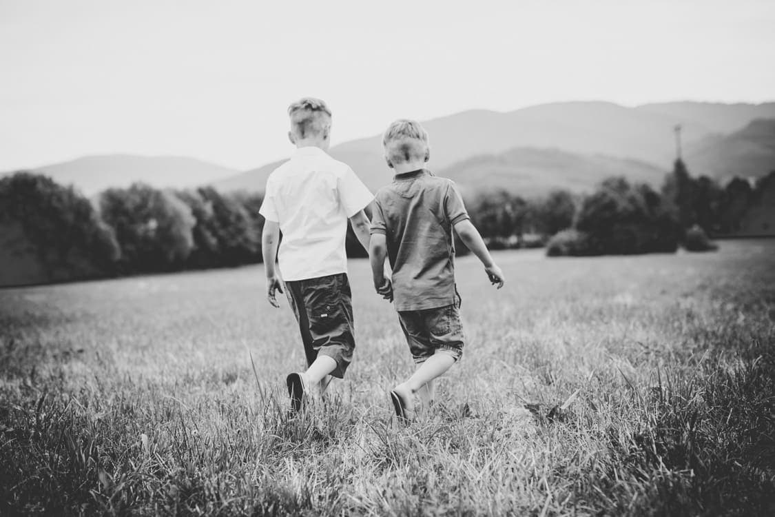 Brüder sind von hinten zu sehen wie sie über eine Wiese laufen