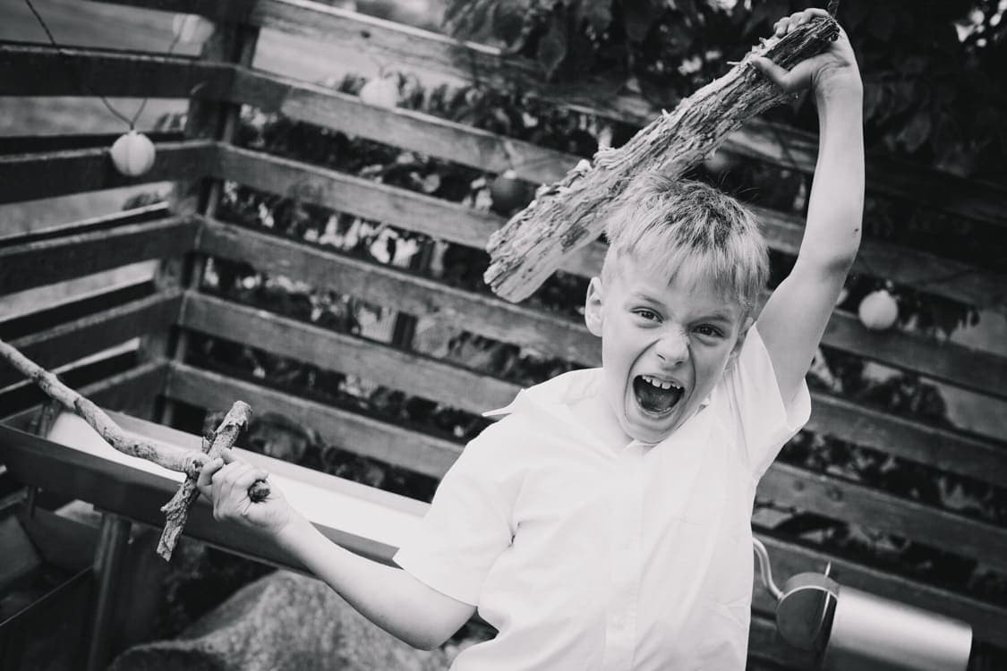 Junge mit Holzschwärten in beiden Händen