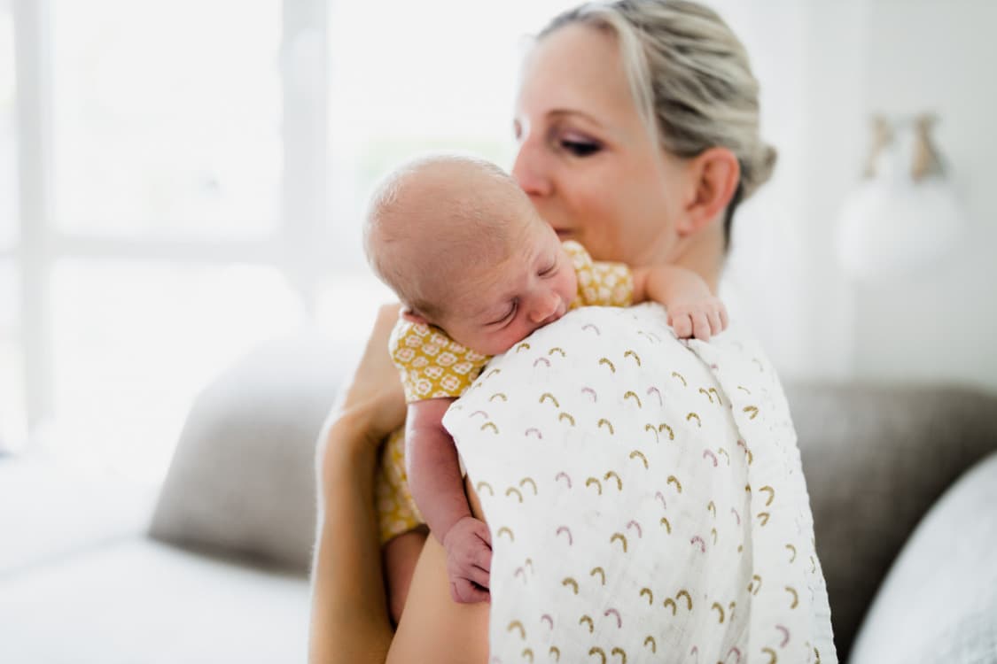 Baby hängt über der Schulter der mutter