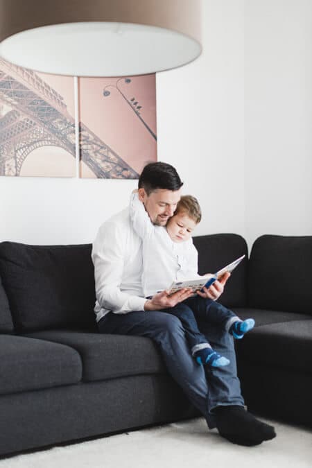 Vater und Sohn lesen ein Buch auf dem Sofa