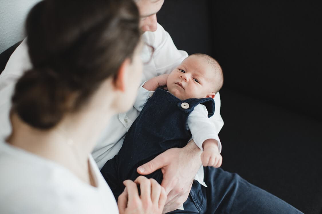 Blick von oben auf Baby im Arm der Eltern