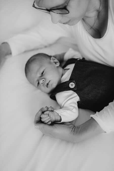 Baby liegt auf dem Bett und die Mutter beugt sich zu ihm