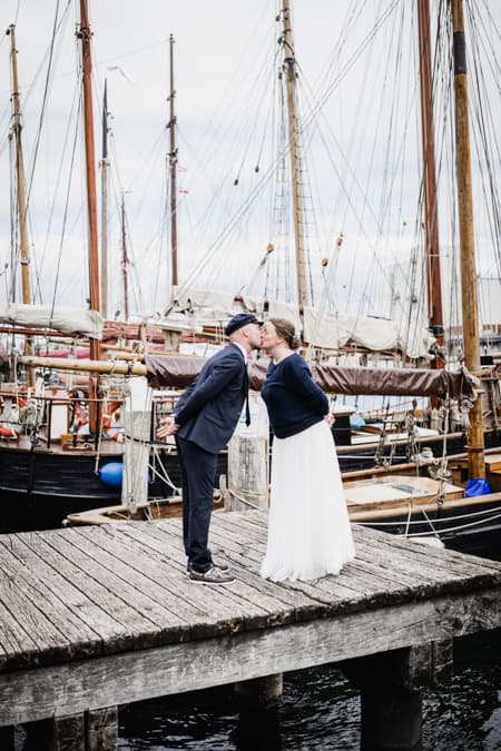 Brautpaar kuesst sich vor einer Hafenkulisse
