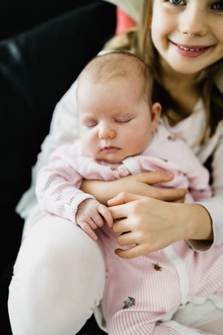 Baby greift Finger der großen Schwester