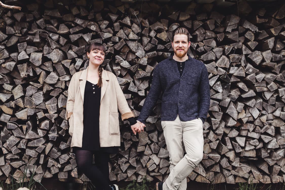 Paar vor Holzscheit hälten sich an den Händen