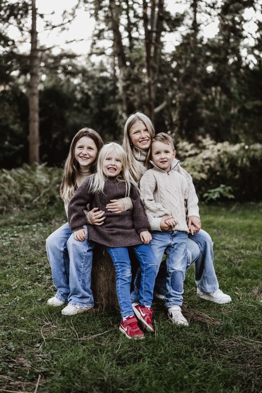 Kinder sitzen auf einem Baumstamm