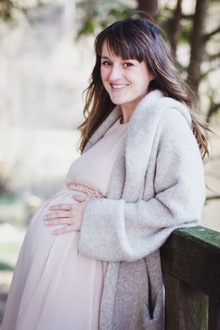 Frau mit Babybauch blickt in die Kamera