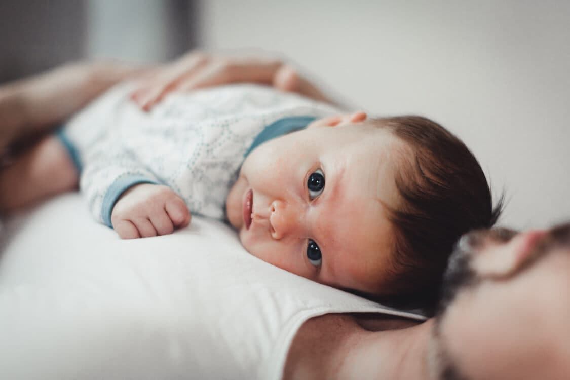 Baby liegt auf der Brust vom Vater