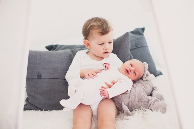 Mädchen hält kleine Schwester auf ihrem Schoß