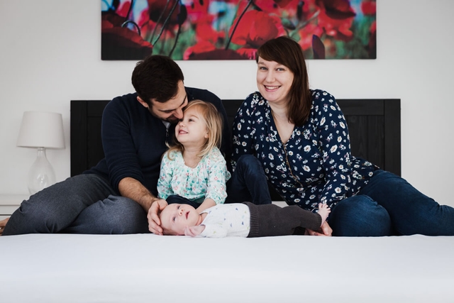 Familie sitzt auf dem Bett mit Tochter und Neugeborenen