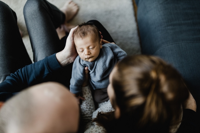 Baby liegt auf dem Schoß der Eltern