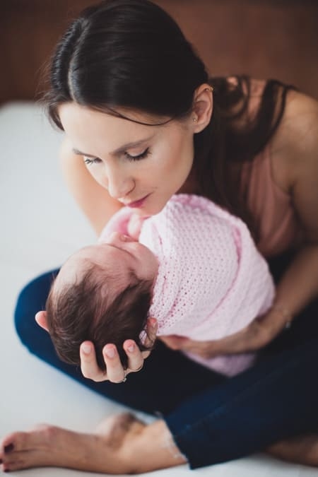 Mutter hält ihr in eine Decke eingewickeltes Baby im Arm und will es küssen
