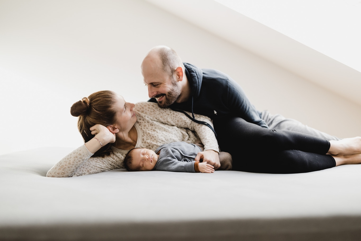 Eltern liegen mit ihrem Baby auf dem Bett