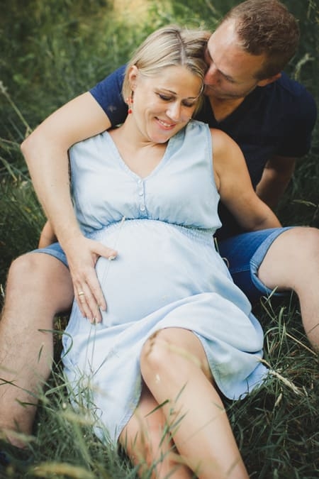 Nahaufnahme von schwangeren Frau mit ihrem Mann die zusammen im Gras sitzen