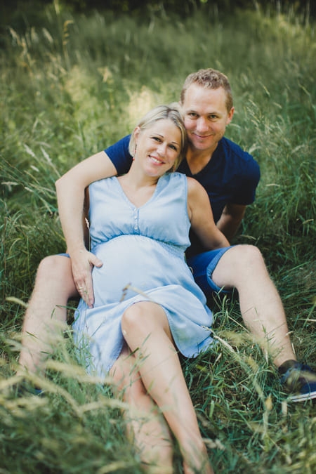 Schwangere Frau mit Mann sitzen zusammen im Gras
