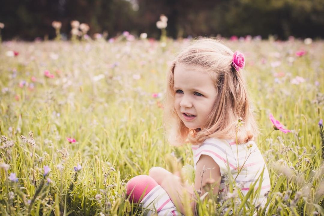 Mädchen sitzt in Blumenwiese
