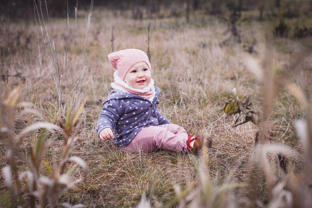 Kleines Mädchen sitzt auf einer Wiese im Herbst