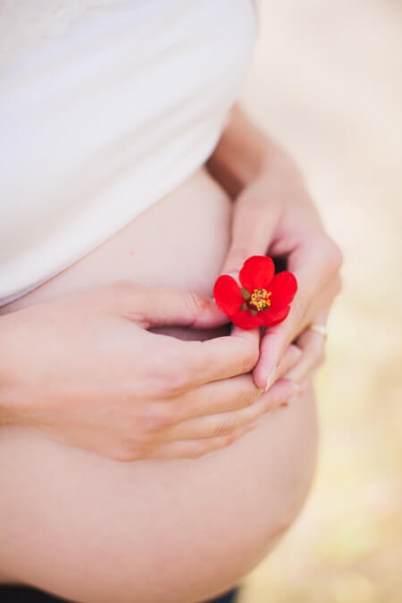 Nahaufnahme von Babybauch mit roter Blume