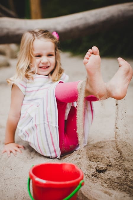 Mädchen spielt mit den Füßen im Sand