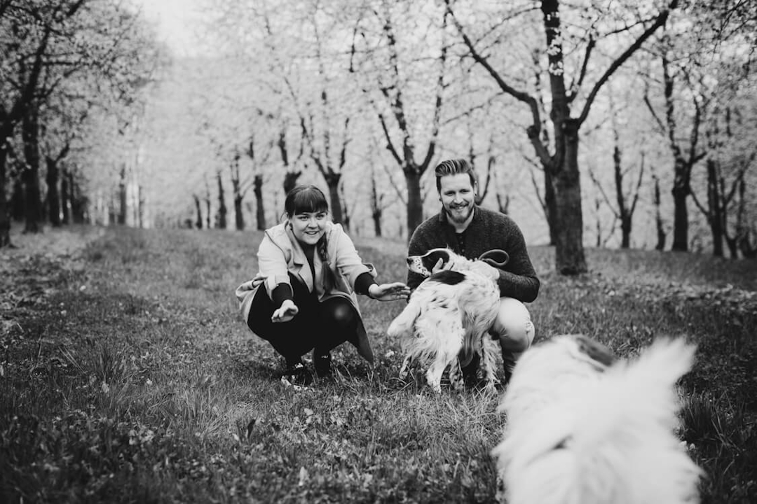 Schwarz weiß Foto von Paar mit herumtollenden Hunden