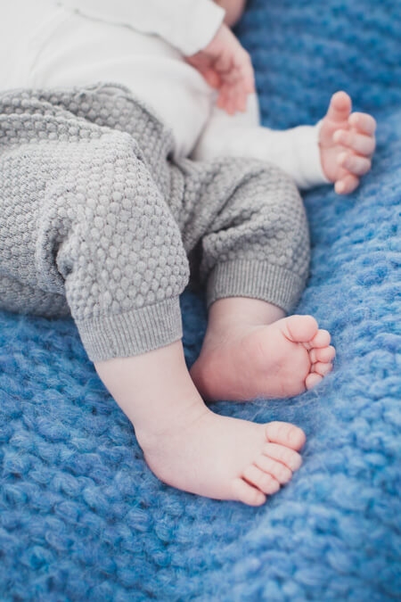 Babyfüße sind auf einer blauen Strickdecke zu sehen
