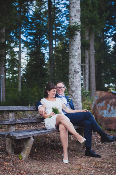 Brautpaar sitzt auf einer Bank im Wald