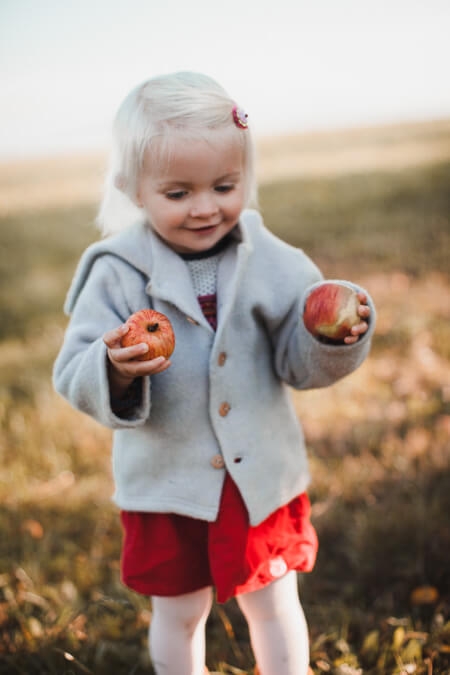Kleines Mädchen mit zwei Äpfeln in den Händen