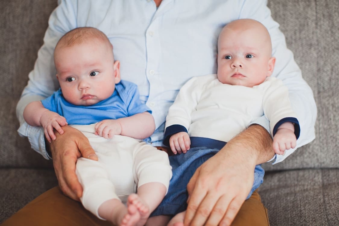 Nahaufnahme von Zwillingsbabys die auf dem Schoß vom Papa sitzen