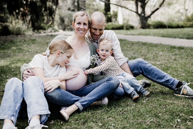 Frau mit Babybauch und Familie auf einer Wiese