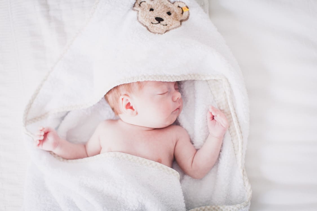 Schlafendes Neugeborenens im Handtuch mit Kaputze 
