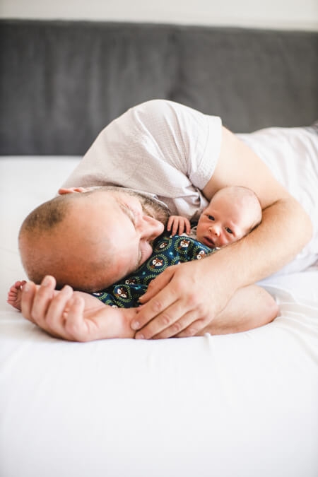 Vater kuschelt auf dem Bett liegend mit ihrem Baby