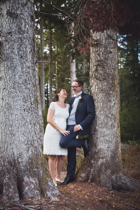 Brautpaar lehnt an einem Baum im Wald