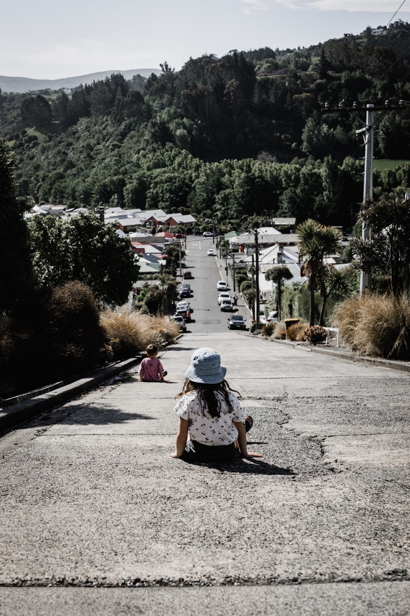Kinder sitzen auf steiler Straße