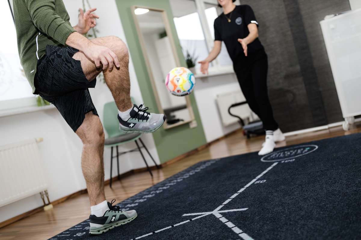 Mann kickt Ball in Physiotherapie Praxis